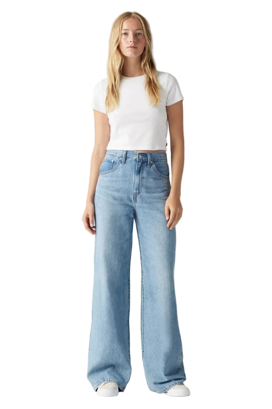 Woman wearing light blue jeans and a white t-shirt on a gray background