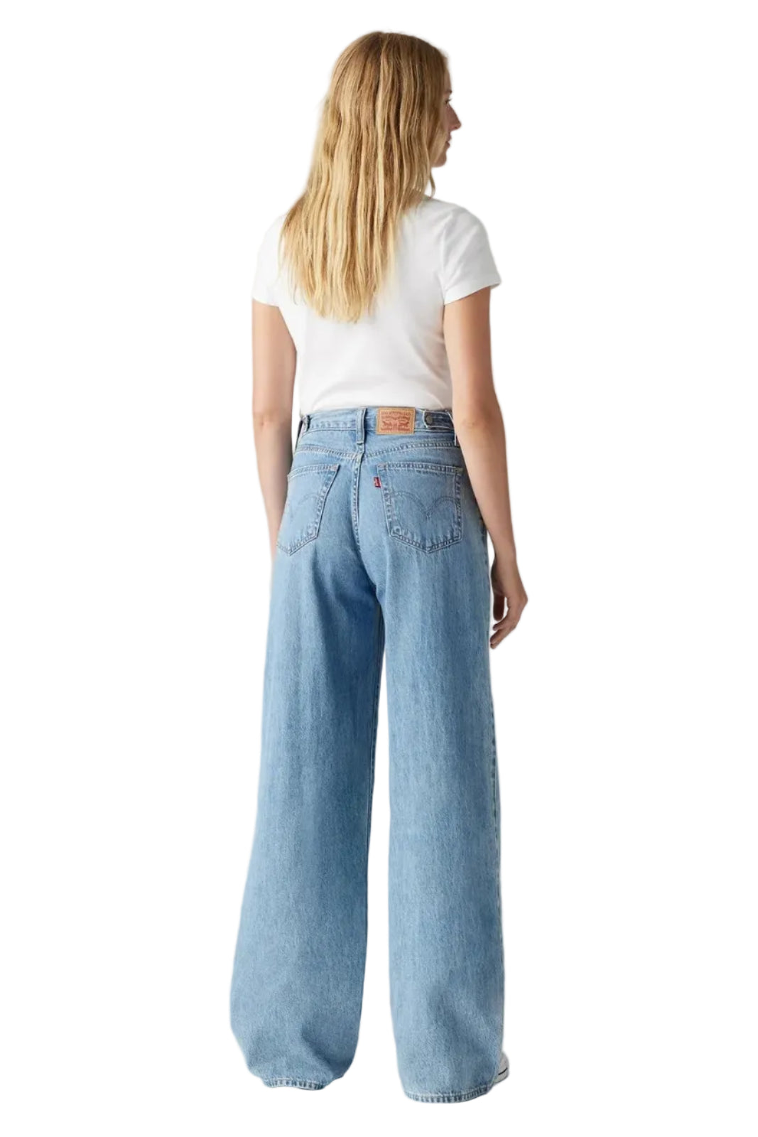 Person wearing light blue jeans and a white t-shirt on a plain background