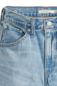Close-up of a pair of light blue jeans with a brand label on a white background