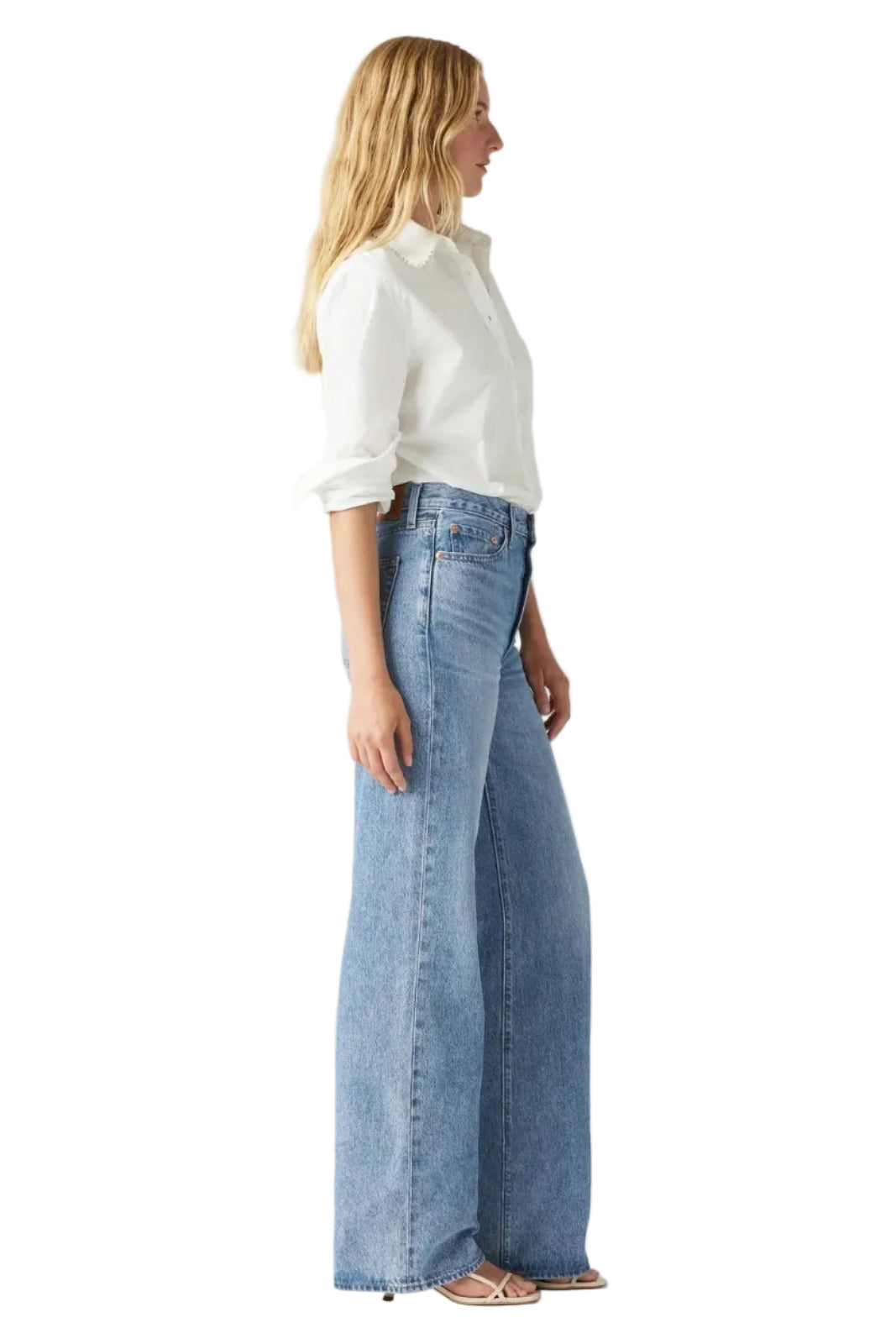 Woman wearing a white blouse and blue jeans on a light gray background