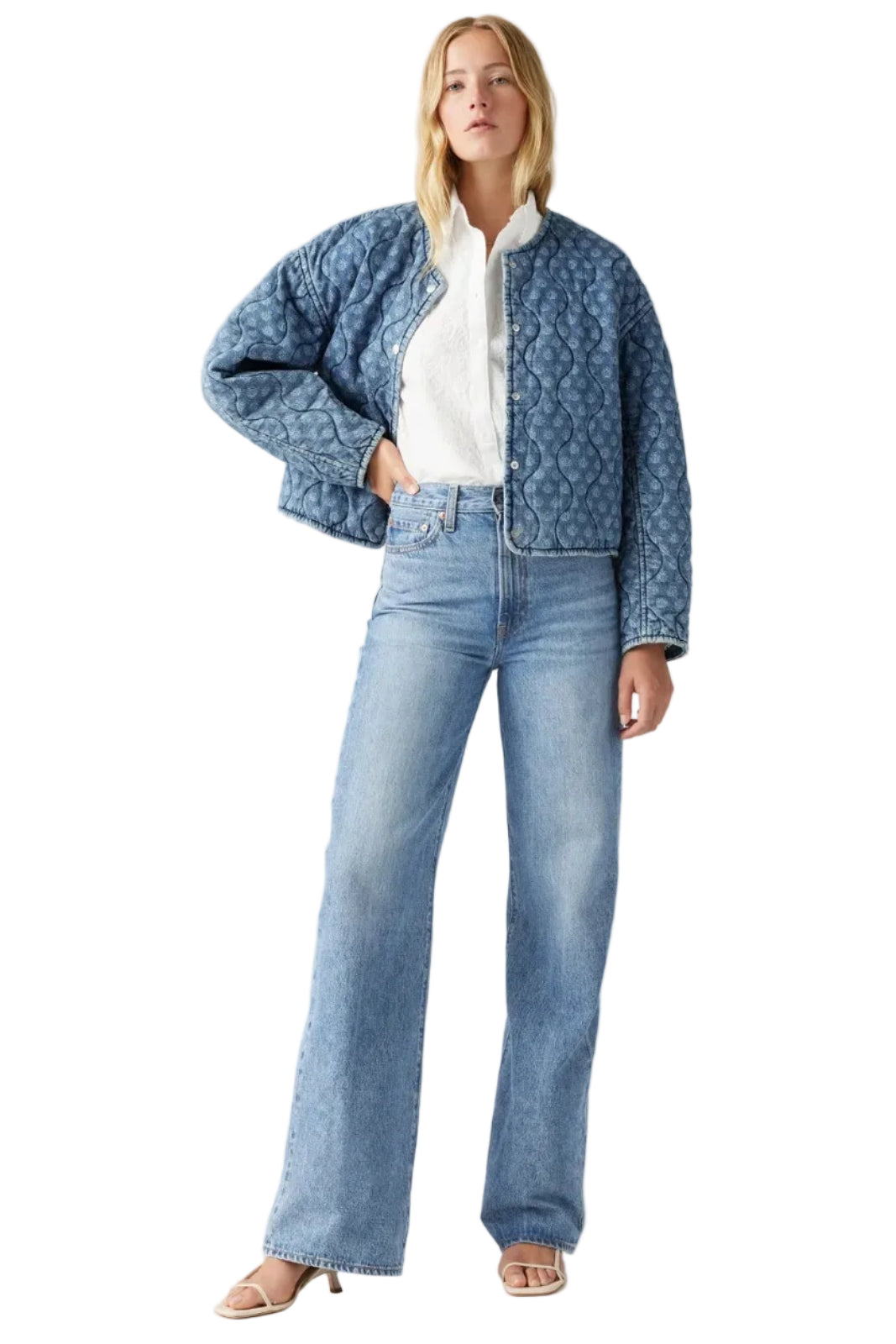 Woman wearing a denim jacket and jeans on a gray background