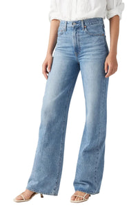 Person wearing light blue jeans on a plain background