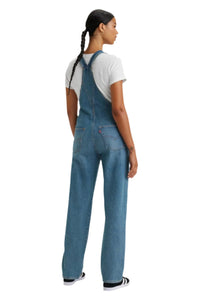 Person wearing blue denim overalls on a white background